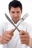chef holding crossed fork and knife