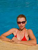 Girl in the swimming pool wearing sunglasses and smiling