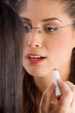 beautician applying lipstick on female lips