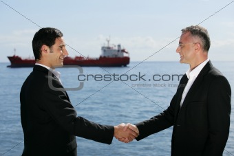 Businessmen shaking hands in front of a cargo boat
