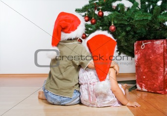 Kids looking at the christmas tree hugging