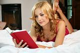 a woman is reading a book in her bed