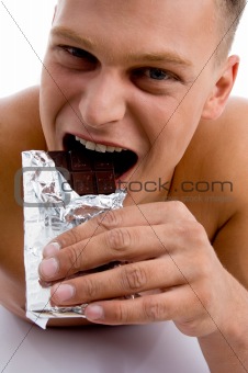 smiling muscular male eating chocolate