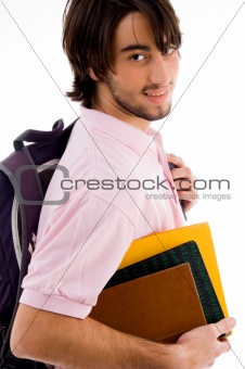 smiling college boy posing with his bag and books