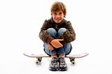 front view of boy sitting on skateboard 