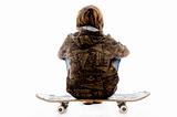 back pose of boy sitting on skateboard 