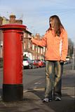 girl posting letter to red british postbox