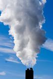 chimney billowing white smoke into blue sky