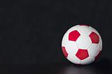 Red and white soccer ball on a black background