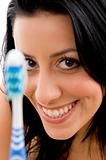 front view of smiling woman with toothbrush on white background