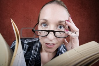 Peprlexed woman with big eyes reading a book