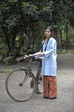 Malay girl push old bicycle in her village