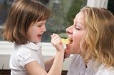 Daughter Having Fun Feeding Mom an Apple Slice