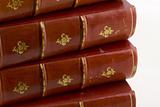 stack of old books in red leather with gold engravings