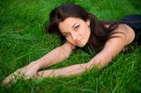 Beautiful young brunette rests on the green grass
