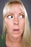 Shocked Blond Woman with Funny Face against a Grey Background
