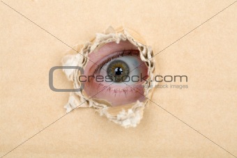 Eye looking from a hole in a cardboard