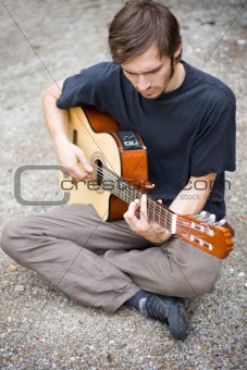 rough country guy playing his guitar in the backyard
