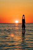 Silhouette of the young woman with hands upwards on a bay on a s