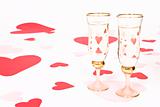 two glasses  of white wine on white heart covered background