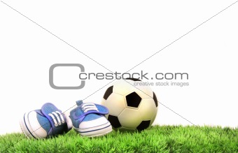 Child's shoes with rubber ball on grass