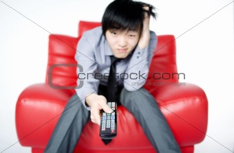 The young man in a grey shirt watches TV