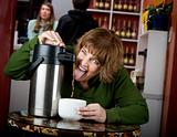 Woman drinking coffee directly from a dispenser