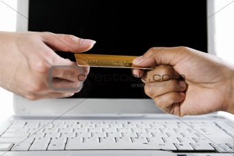 Hand over gold credit card as laptop on background