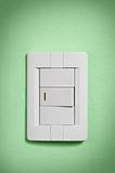White light switch on green wall.