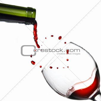 Pouring red wine in goblet on yellow background