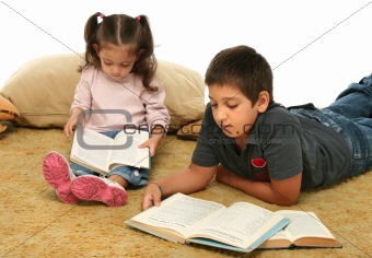 Brother and sister reading books on the floor