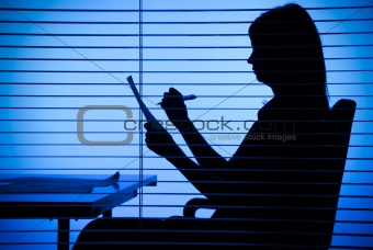silhouette of woman with papers (view through the blind)