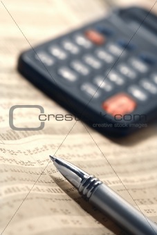 Close-up of a pen and a calculator on a financial newspaper