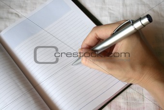 hand holding pen writing on note book