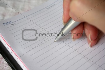 hand holding a pen writing on note book