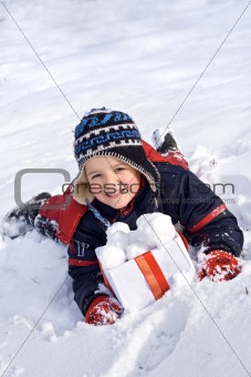 Happy boy in the snow with snowballs in a box