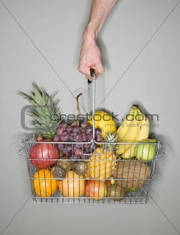 Hand holding a basket of fruits