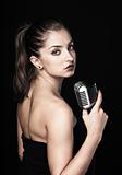Beautiful woman holding retro microphone on black background