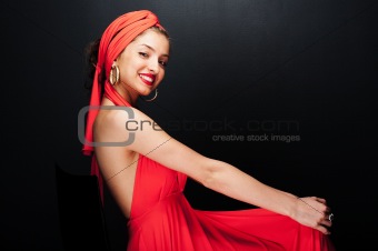 Beautiful cheerful girl in red dress on black background