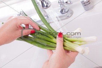 Woman Washing Onions in the Kitchen Sink.
