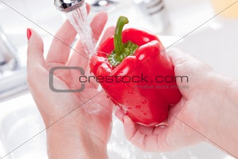 Woman Washing Red Bell Pepper in the Kitchen Sink.