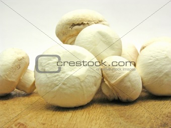 White  mushrooms on a brown wooden plate