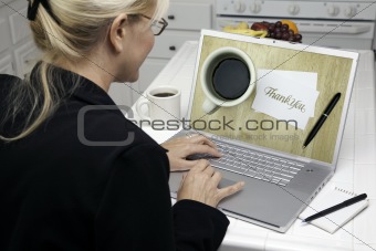 Woman In Kitchen Using Laptop with Thank You Image on Screen. Screen can be easily used for your own message or picture. Picture on screen is my copyright as well.