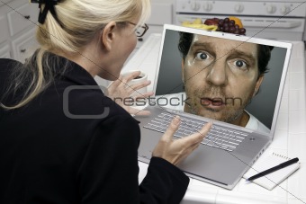 Shocked Woman In Kitchen Using Laptop with Strange Man on Screen. Screen can be easily used for your own message or picture. Picture on screen is my copyright as well.