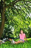 Teenage girl relaxing in a park with her bicycle