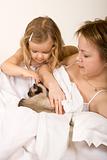 Little girl and her mother in bed with a kitten