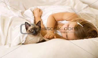 Little girl in bed with her kitten