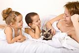 Woman and kids with a kitten lazying in the bed