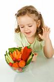 Little girl looking at a bowl of vegetables
