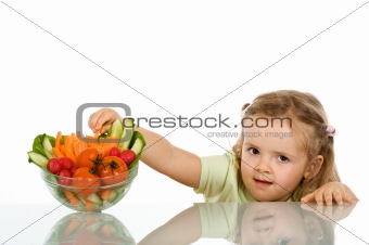 Little girl stealing a vegetable from a bowl